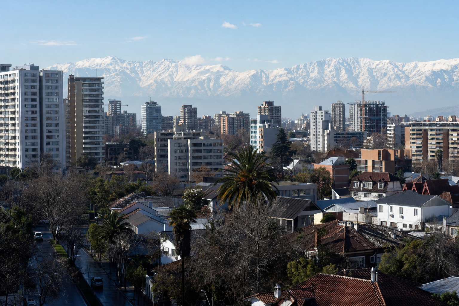 Vista de techos y edificios de Ñuñoa y Providencia con la cordillera nevada en invierno