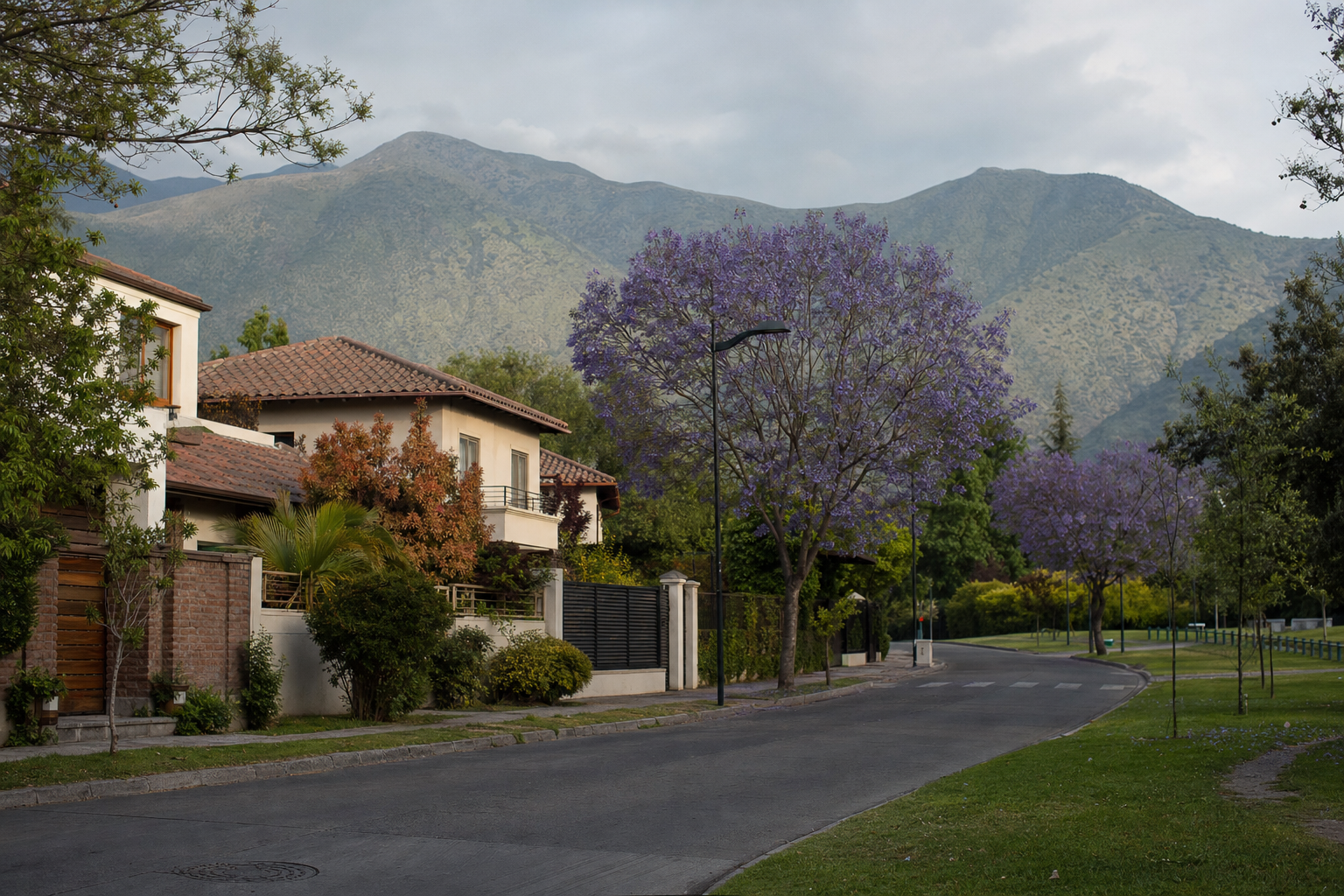 Calle residencial de Los Dominicos, Las Condes, con casas, jacarandás y la precordillera al fondo